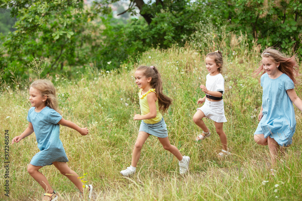 Obraz premium Angels. Kids, children running on green forest. Cheerful and happy boys and girs playing, laughting, running through green blooming meadow. Childhood and summertime, sincere emotions concept.