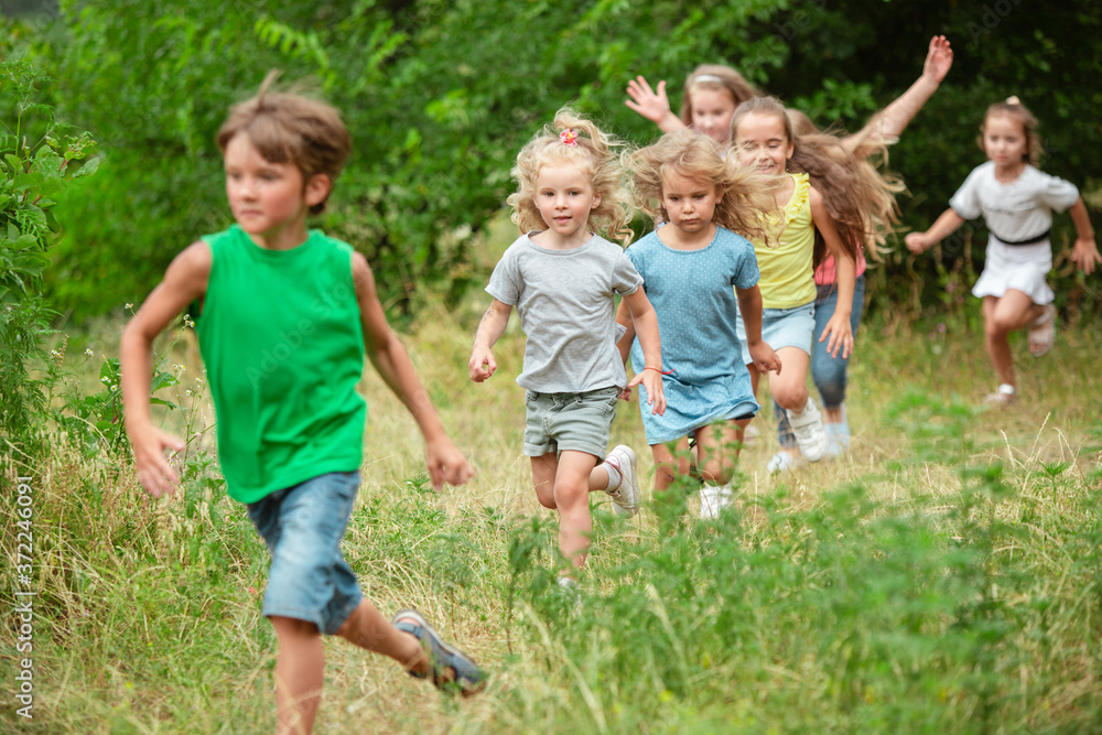 Angels. Kids, children running on green forest. Cheerful and happy boys and girs playing, laughting, running through green blooming meadow. Childhood and summertime, sincere emotions concept. Angels. Kids, children running on green forest. Cheerful and happy boys and girs playing, laughting, running through green blooming meadow. Childhood and summertime, sincere emotions concept.