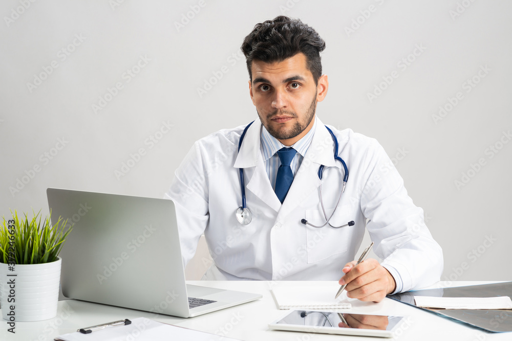 Handsome doctor sitting at desk in office