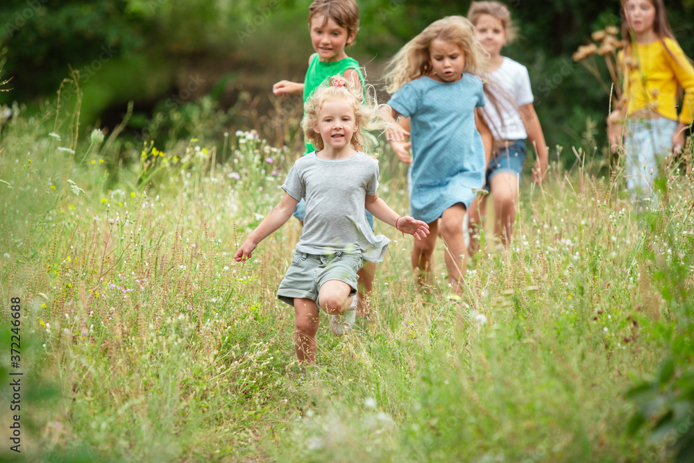 Angels. Kids, children running on green forest. Cheerful and happy boys and girs playing, laughting, running through green blooming meadow. Childhood and summertime, sincere emotions concept. Angels. Kids, children running on green forest. Cheerful and happy boys and girs playing, laughting, running through green blooming meadow. Childhood and summertime, sincere emotions concept.