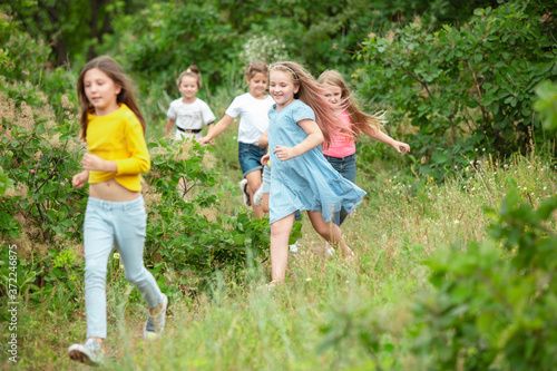 Best time. Kids, children running on green forest. Cheerful and happy boys and girs playing, laughting, running through green blooming meadow. Childhood and summertime, sincere emotions concept.