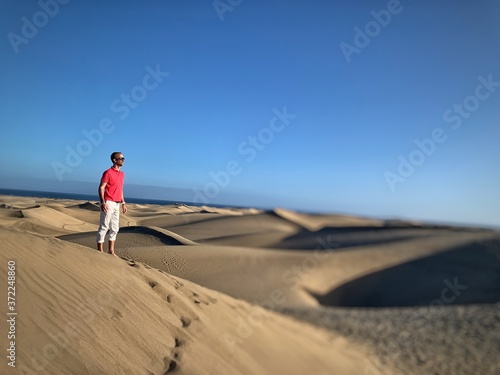Jeune homme devant des dunes de sable désertique