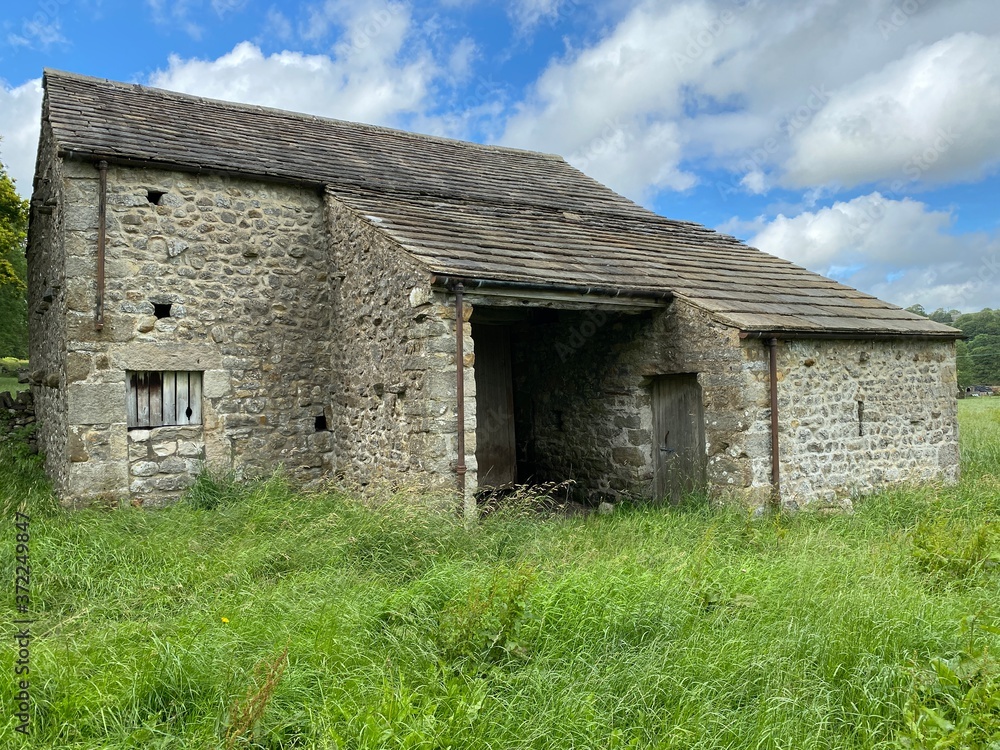 Old barn, with a stone slate roof, in an uncut field, on a cloudy day in, Malham, Skipton, UK Old barn, with a stone slate roof, in an uncut field, on a cloudy day in, Malham, Skipton, UK