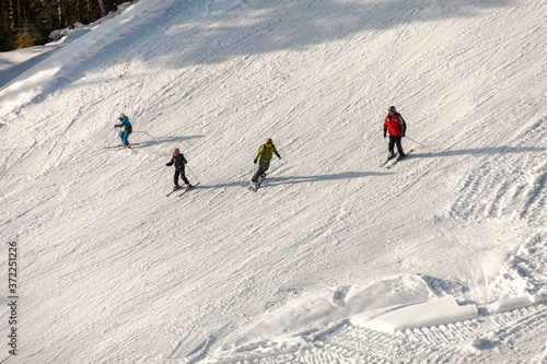 skiers and snowboarders descend from the ski slope