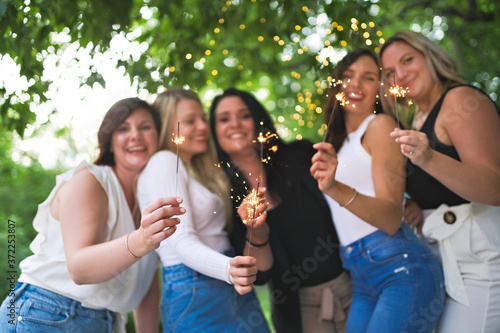 Group of girls friends having good time together with bengal lights