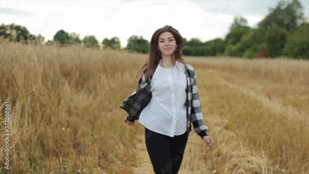 Rest in the village. Nature. A young girl runs and whirls near a wheat field approaching the camera Rest in the village. Nature. A young girl runs and whirls near a wheat field approaching the camera