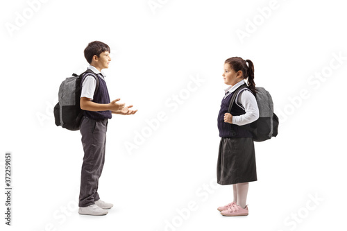 Full length profile shot of pupils in uniforms having a conversation