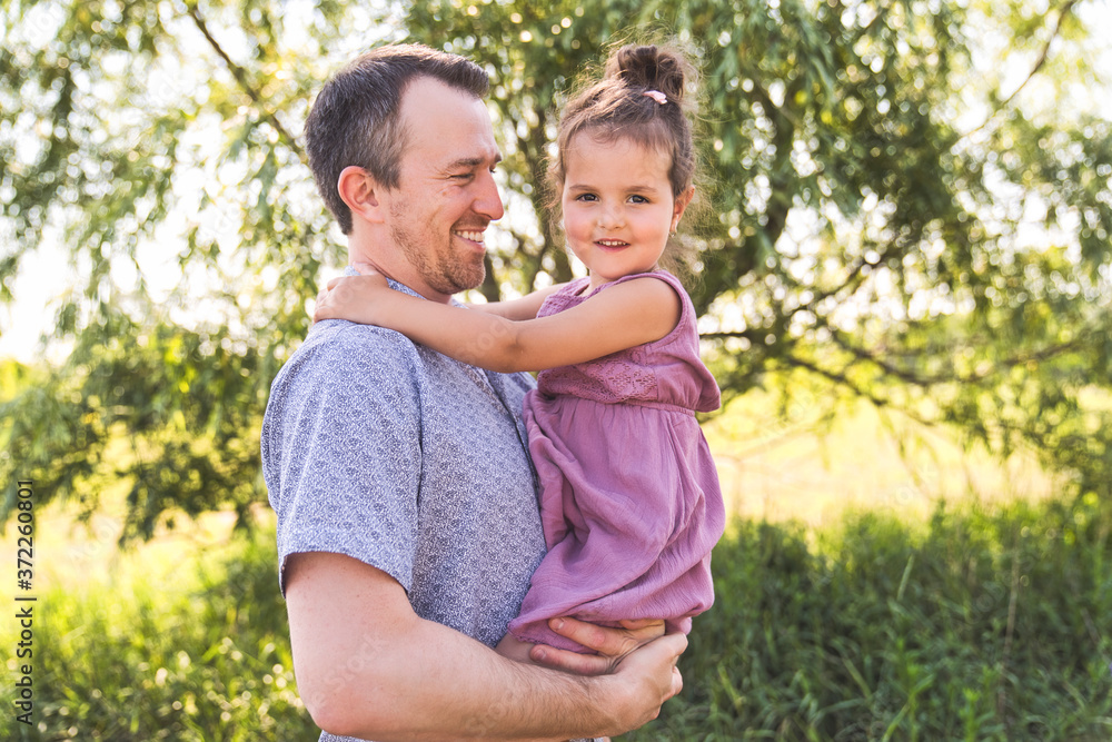 Obraz premium Father with small daughter standing outdoors by tree.