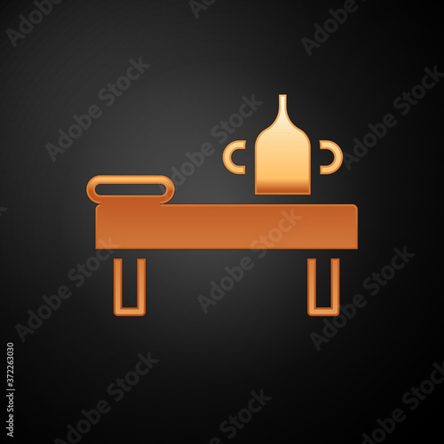 Gold Massage table with oil icon isolated on black background. Vector.