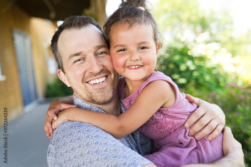 Father with small daughter standing outdoors by tree. Father with small daughter standing outdoors by tree.
