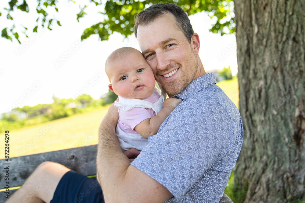 Father with baby girl standing outdoors by tree. Father with baby girl standing outdoors by tree.
