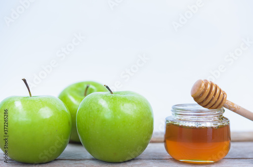 Jewish holiday, Apples Rosh Hashanah on the photo have honey in jar have green apples on wooden with white background photo