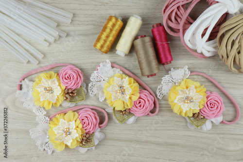 A bouquet of flowers made out of fabric cloth textile in beautiful pastel colors placed on white wooden table that can be used as hair accessory, decoration, and embellishment