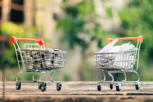 Close up coins and receipts paper on mini shopping cart with natural light background (Business and finance concept)