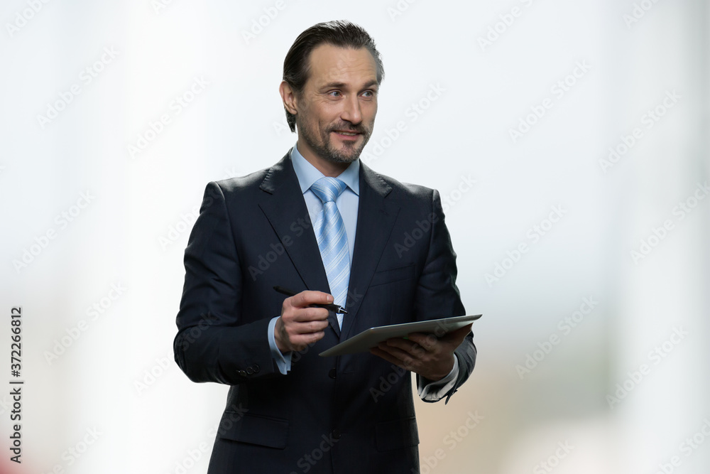 Handsome businessman making notes in his tablet. Male architect or graphic designer working on pc tablet with a stylus pen. People, business, technology concept. Handsome businessman making notes in his tablet. Male architect or graphic designer working on pc tablet with a stylus pen. People, business, technology concept.