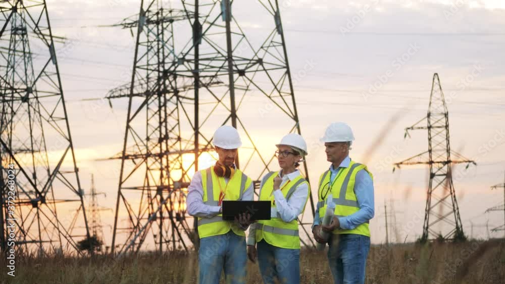 Power engineers are having a discussion in the field at sunset. Energy saving, energy efficiency concept. Power engineers are having a discussion in the field at sunset. Energy saving, energy efficiency concept.