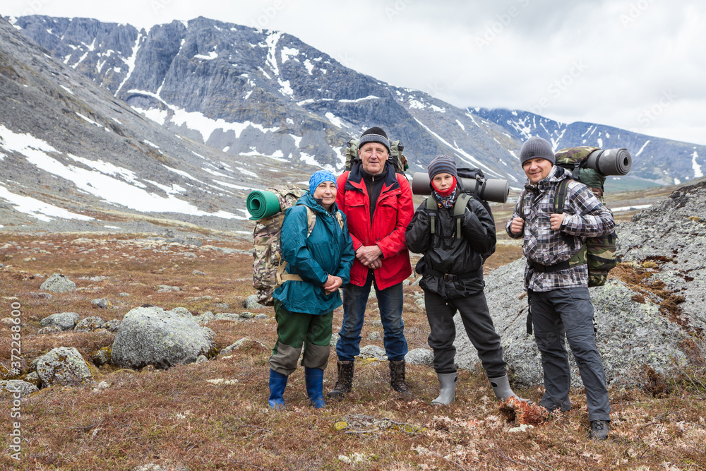 Team of Caucasian hikers with backpacks, four people standing in mountain valley, portrait with copyspace Team of Caucasian hikers with backpacks, four people standing in mountain valley, portrait with copyspace