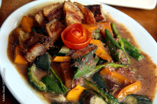Filipino dish called Pinakbet or mixed vegetables in fish paste sauce with crispy pork belly photo