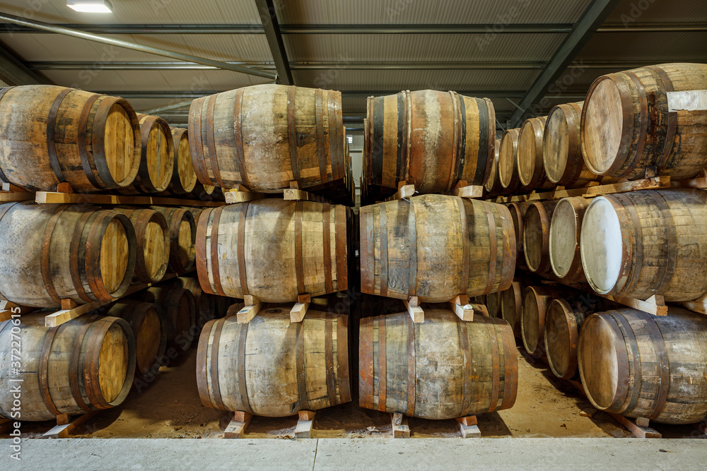 Rows of stacks of traditional full whisky barrels, set down to mature, in a large warehouse