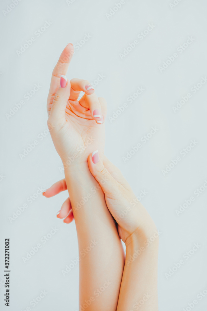 Naklejka premium Female hands with french manicure on gray background