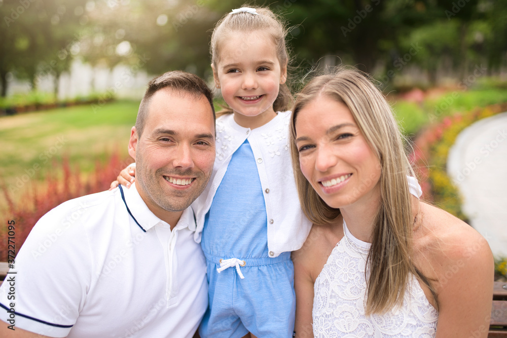 Happy young family sit on bench outside in summer day Happy young family sit on bench outside in summer day