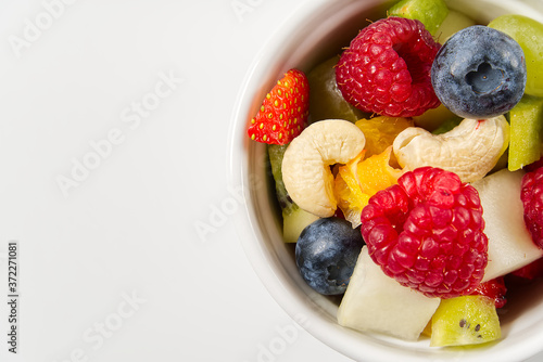Bowl of healthy fresh fruit salad on white background  top view copy space.