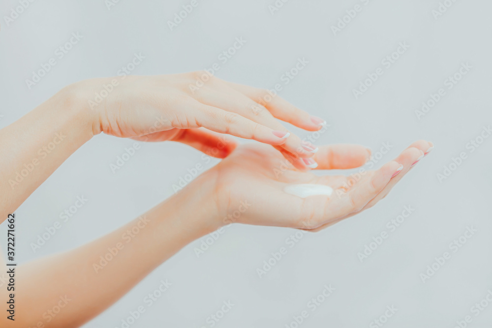 Woman with french manicure applies cream to her hands