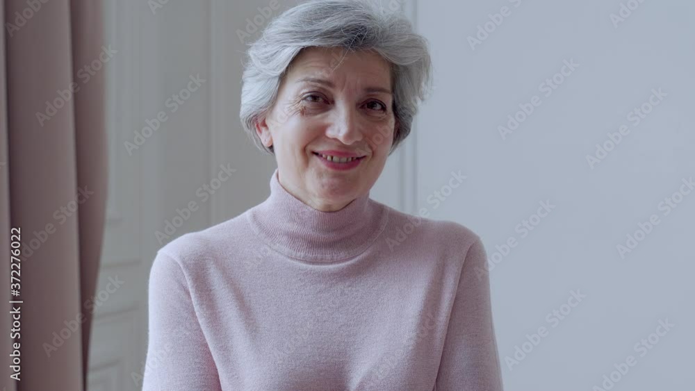Beautiful old woman with gray hair smiles standing at home Beautiful old woman with gray hair smiles standing at home