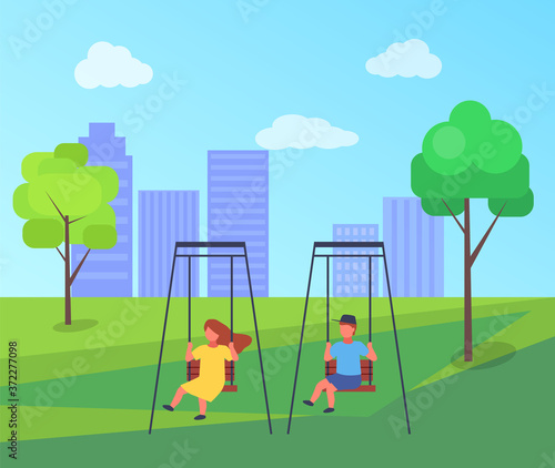 Children ride on a swing in the park or the playground. Girl and boy have fun, kids playing. Fresh air outdoor activity. Group of happy kids playing in city square. Various children on playground