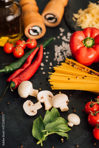 selective focus of raw Italian spaghetti with vegetables on black background