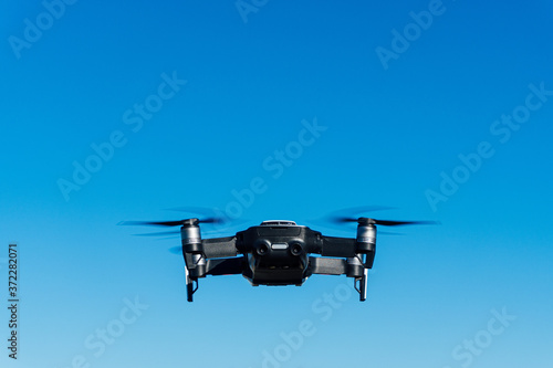 Fototapeta Naklejka Na Ścianę i Meble -  Generic image of a white drone flying across a blue sky. Remote control equipment for aerial surveillance.