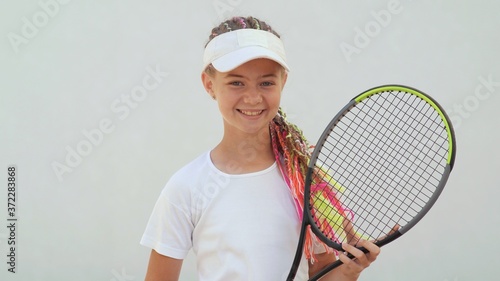 Portrait of a young girl with dreadlocks and a tennis racket on a white background. © Довидович Михаил