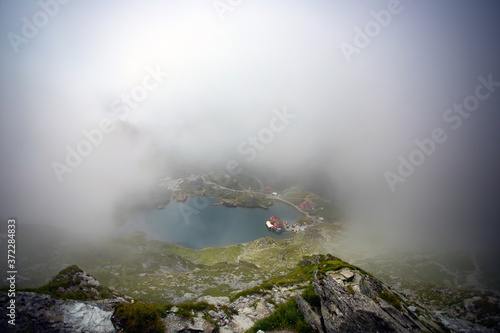 alea Lake covered by fog, Fagaras Mountains, Romania in the summer.