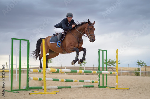 Jockey riding a horse jumping an obstacle on the track. Jumping sport.