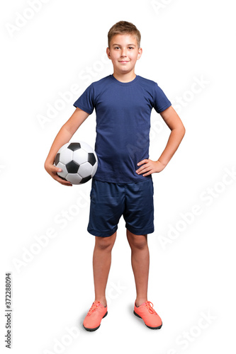 Kid in sport uniform holding a classic soccer ball, looking at camera and smiling isolated on white background