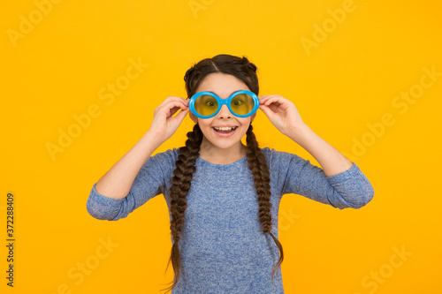 wera uv protective glasses. little beauty wear party glasses. happy childhood. small girl has funny look. kid hairstyle fashion. smiling child with hairdo. teen has party fun. Hair braided in braids