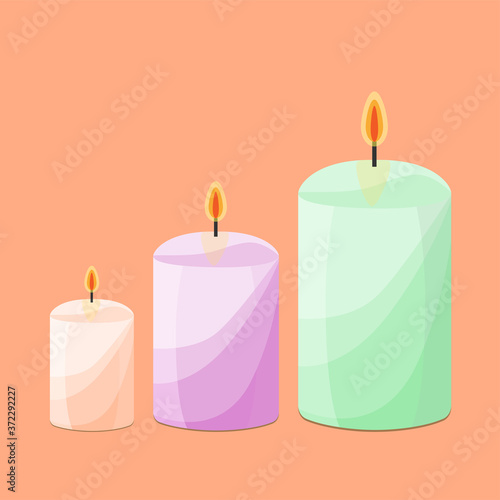 three burning candles of green, pink and light orange on an orange background