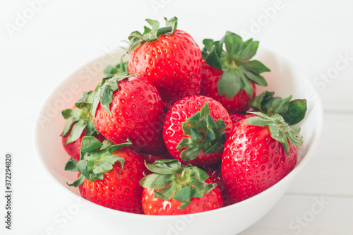 Close up  horizontal shot  fresh strawberries ready to eat in a white bowl on a white background. Selective focus  concepts