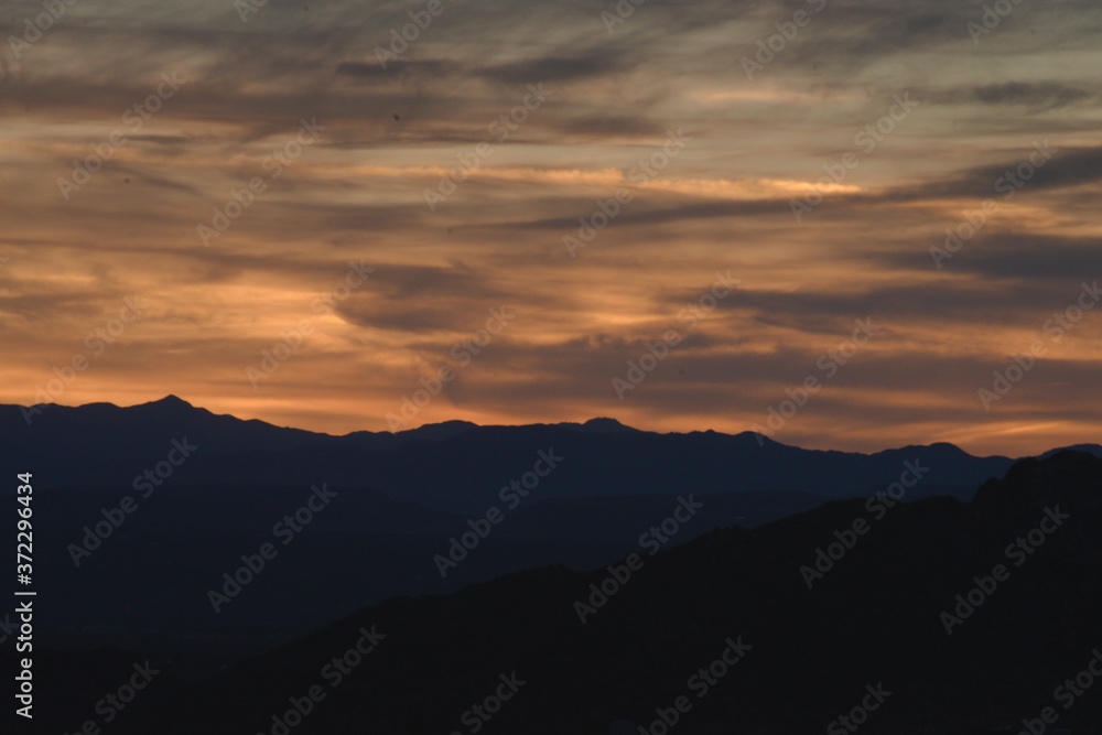 Its right after sunset in southern California desert, with a colorfully illuminated sky, while a mountain range is silhouetted landscape.  The daram created with light and cloud formation . 