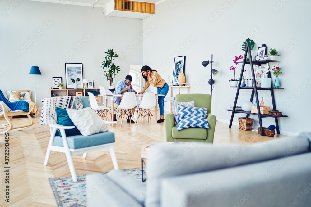 Obraz premium Male and female colleagues spending time together on learning and doing homework at home interior with modern furniture, couple in love having working process in living room making planning