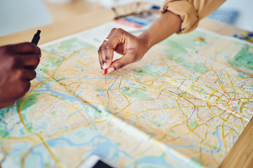 Cropped image of woman's hand pointing on mark on cartography planning adventure route on journey, top view of map of country checking direction and location for explore during travel vacation.