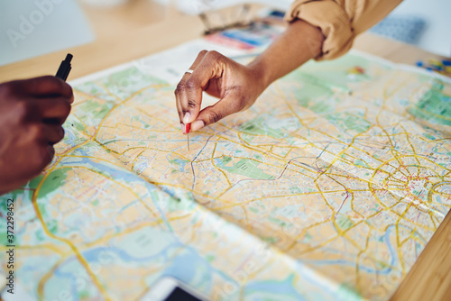 Cropped image of woman's hand pointing on mark on cartography planning adventure route on journey, top view of map of country checking direction and location for explore during travel vacation. photo