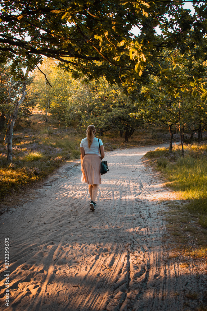 Fototapeta premium A blonde girl exploring late summer nature with golden sunset