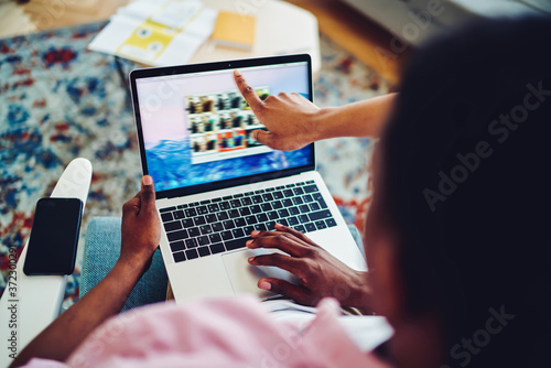 Cropped image of male and female hands pointing on web camera on laptop computer for making video call, modern netbook connected to wireless internet at home with application for online chatting .