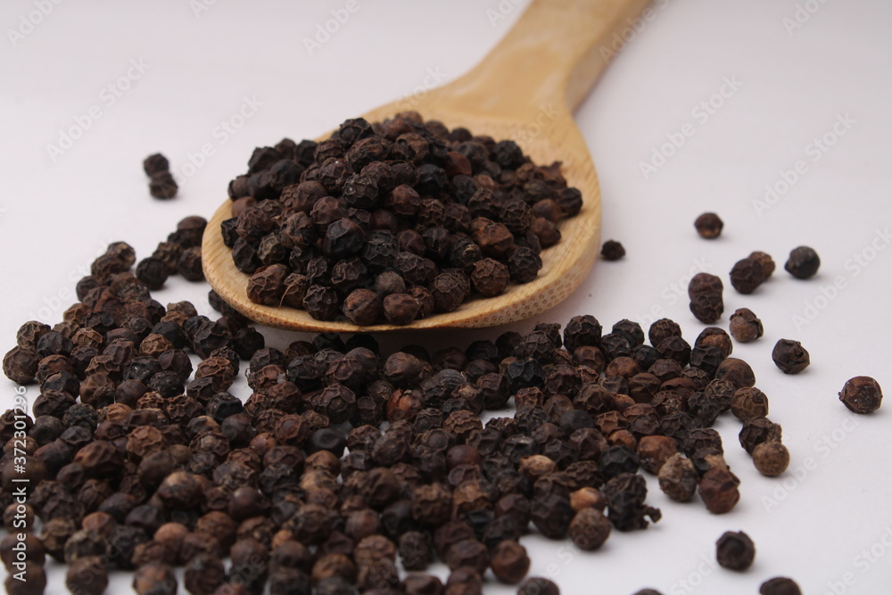 Black pepper in wooden spoon isolated on white background Black pepper in wooden spoon isolated on white background