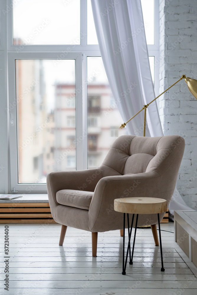 1 beige armchair in a bright room with a window background