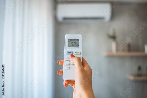 Hand hold remote control directed on the air conditioner. Woman hand using remote control open air conditioning 25 degrees. Open air 25 degrees, is temperature, save energy