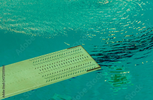 a springboard to dive into the pool / the first floor of a trampoline in the background water of a swimming pool 