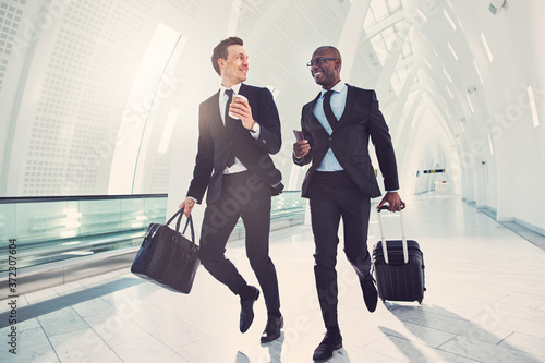 Foto Two smiling businessmen rushing through an airport for a flight