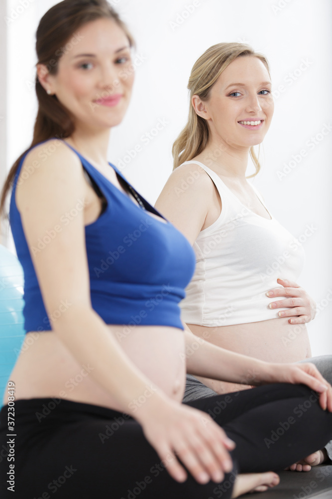 two pregnant sports models do gymnastic exercises